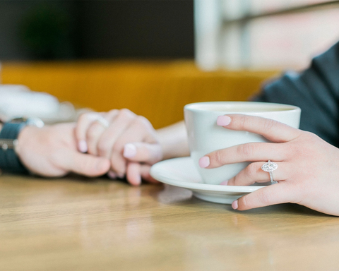 a couple enjoying coffee with a halo engagement ring shown in the picture